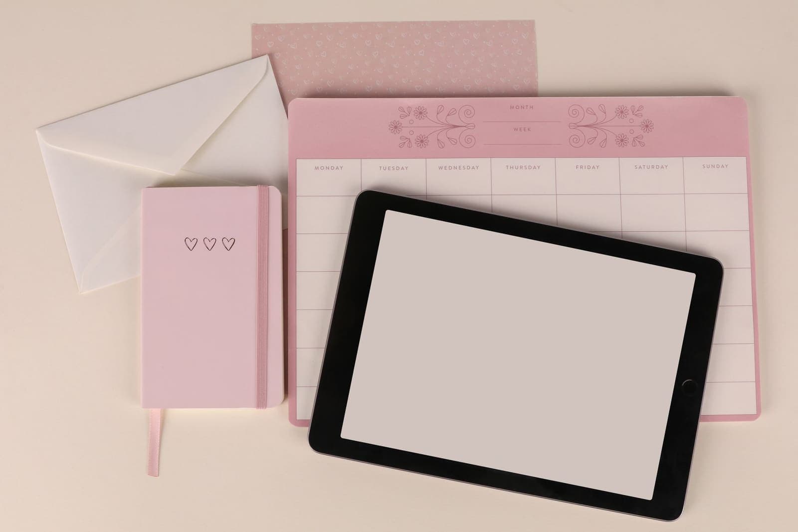 A paper planner open beside a digital tablet showing a weekly schedule