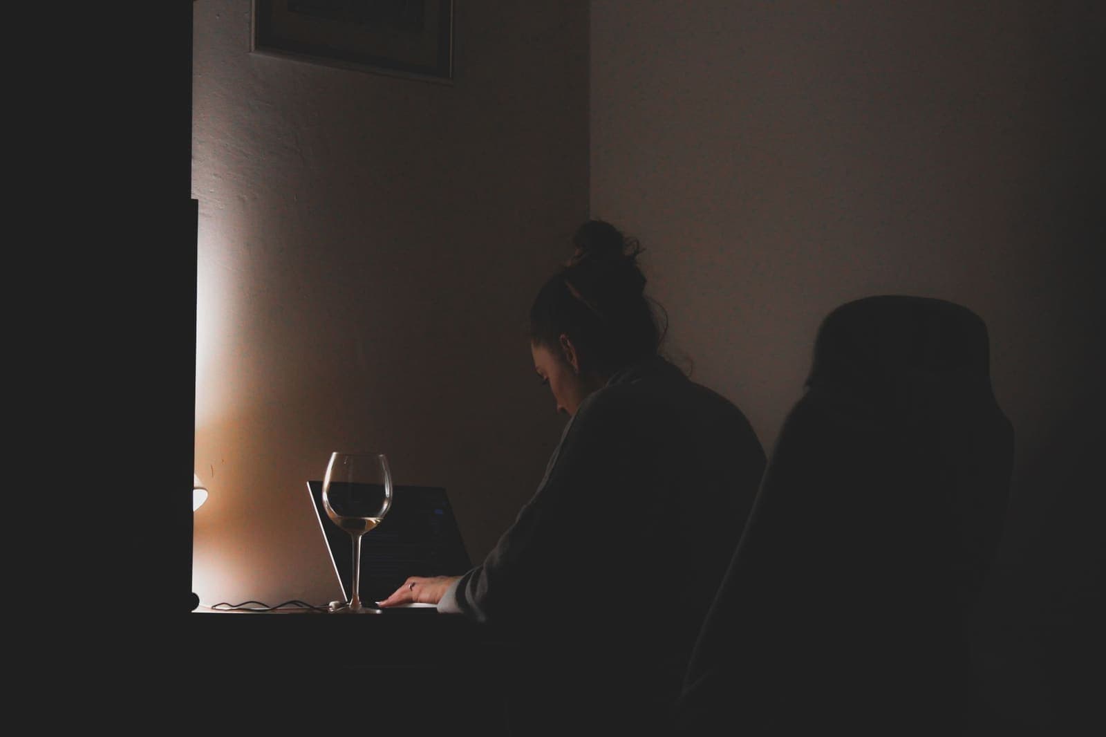 Person working on a laptop at a desk in the evening light