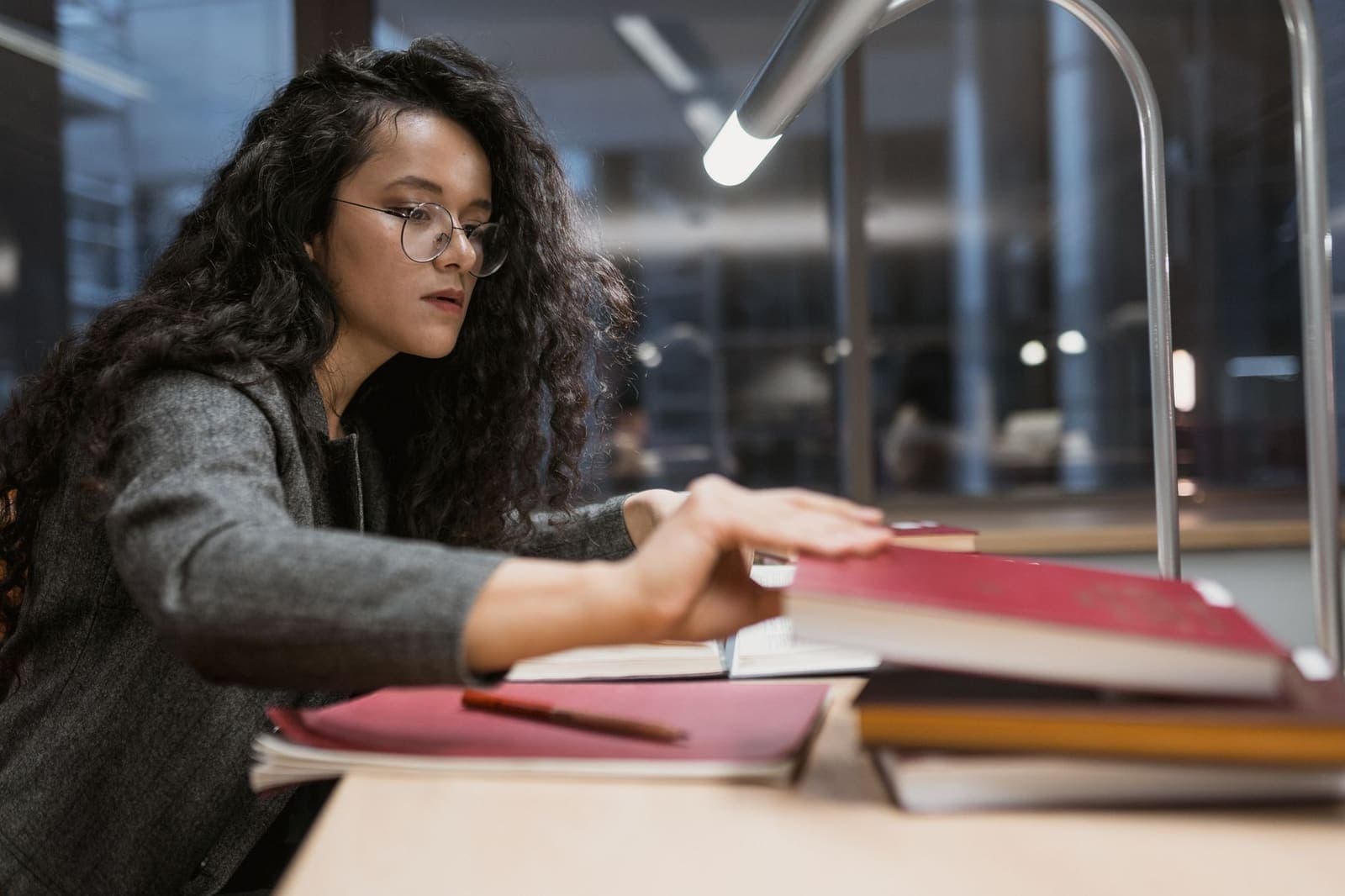 Student sitting at a desk surrounded by textbooks and a notebook, focused on studying