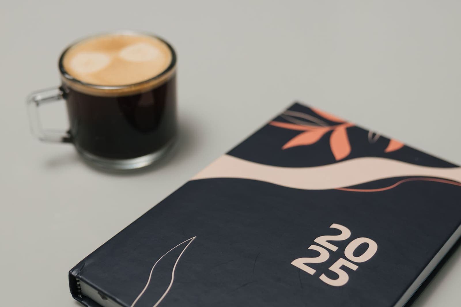 A cup of coffee beside an open planner notebook on a morning desk